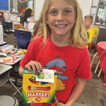 Child holding markers with You’re Draw-some printable Valentine tag for a classroom Valentine