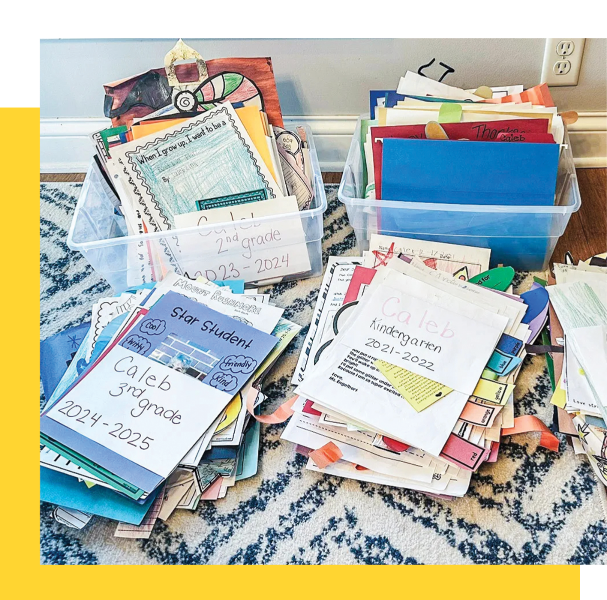 Two clear plastic bins filled with assorted school and memory keepsake items, including papers, folders, and small decorative pieces, arranged on a patterned rug in a home setting.