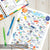 Colorful '31 Days of Kindness for Kids' activity sheet on a wooden surface with markers.